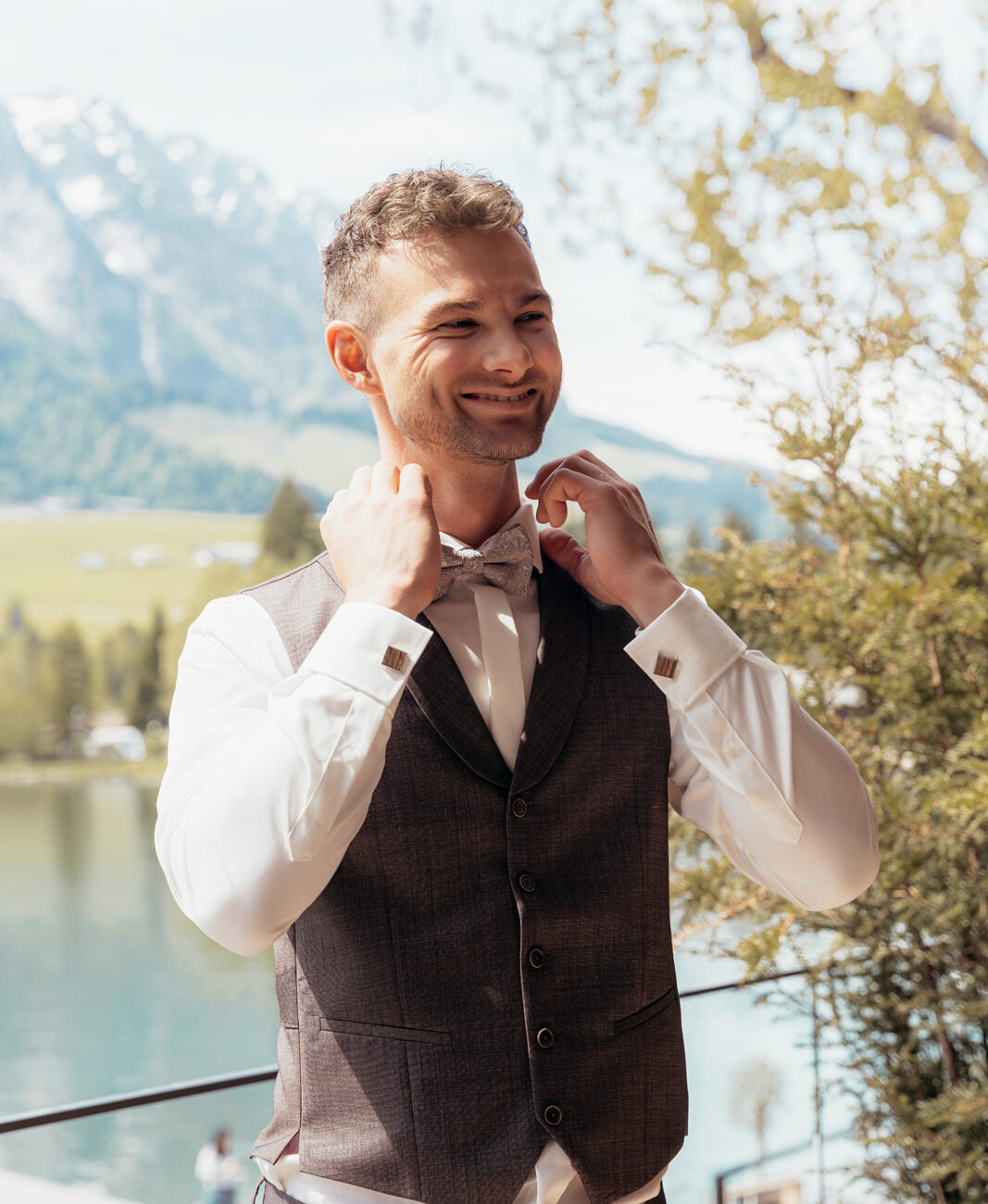 Stilvoller Bräutigam in braun-grauem Hochzeitsanzug mit Fliege am Walchsee
